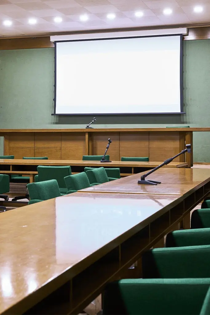 Sale Riunioni A e B - tavolo relatori con microfoni davanti allo schermo