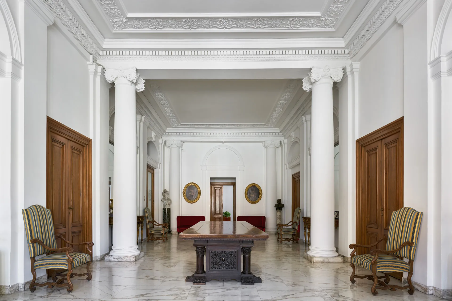 Salone con colonne, pavimento in marmo e tavolo centrale