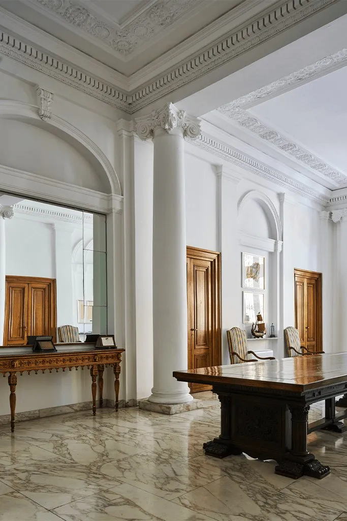 Salone con colonne, pavimento in marmo e scrivania in legno